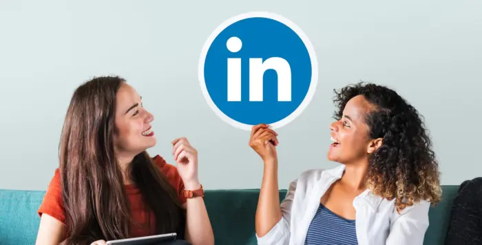 due ragazze tengono in mano un cartello con rappresentato il logo di linkedin